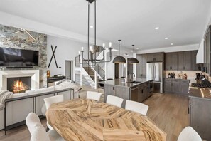 A modern kitchen with a central island, built-in appliances, and a staircase leading to an upper level. - Breathtaking 5-Bed Mountain Modern Home (Big Sky)