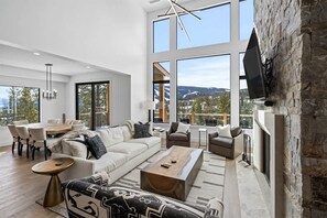A spacious living room with a large window, a fireplace, and a dining area.