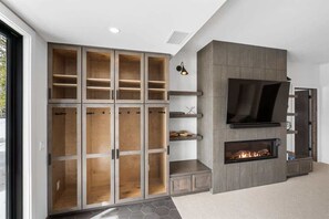 A modern living room with a built-in fireplace, a large TV, and a multi-tiered shelving unit.