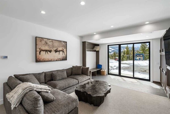 A modern living room with a sectional sofa, a coffee table, and a large painting of animals.