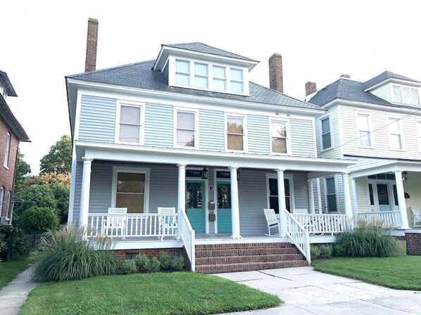 A two-story house with a front porch, a garage, and a brick chimney.