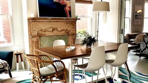 A dining area with a wooden table, white chairs, and a patterned rug. - Salt Box II, One Block to the Beach (Cape Charles)