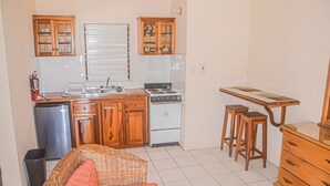 Una cocina compacta con armarios de madera, estufa, lavamanos y un refrigerador pequeño.