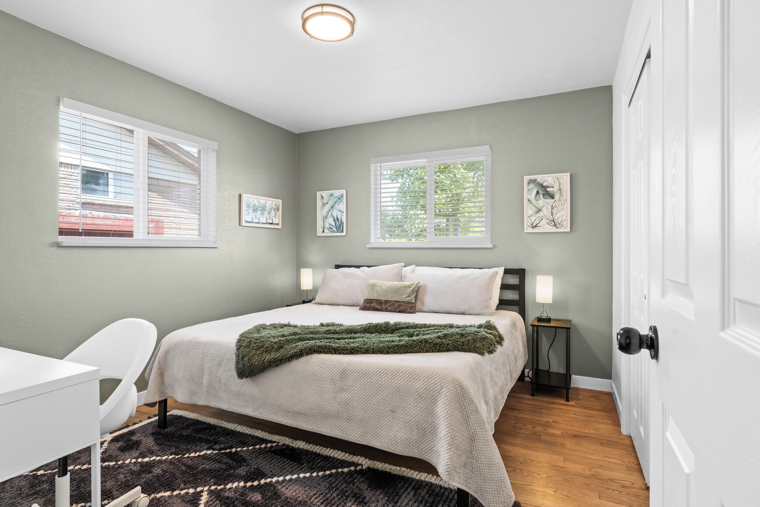 Un dormitorio con cama, mesitas de noche, un escritorio y una silla.