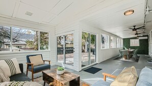 A spacious, well-lit room with a large sliding glass door leading to an outdoor area, a dining table with chairs, and a variety of seating options.