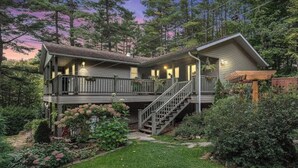 A two-story house with a covered porch, a staircase, and a garden.