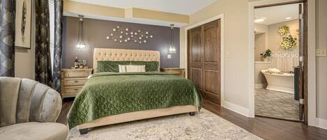 A bedroom with a bed, a chair, a ceiling fan, a nightstand, and a wall-mounted light fixture.