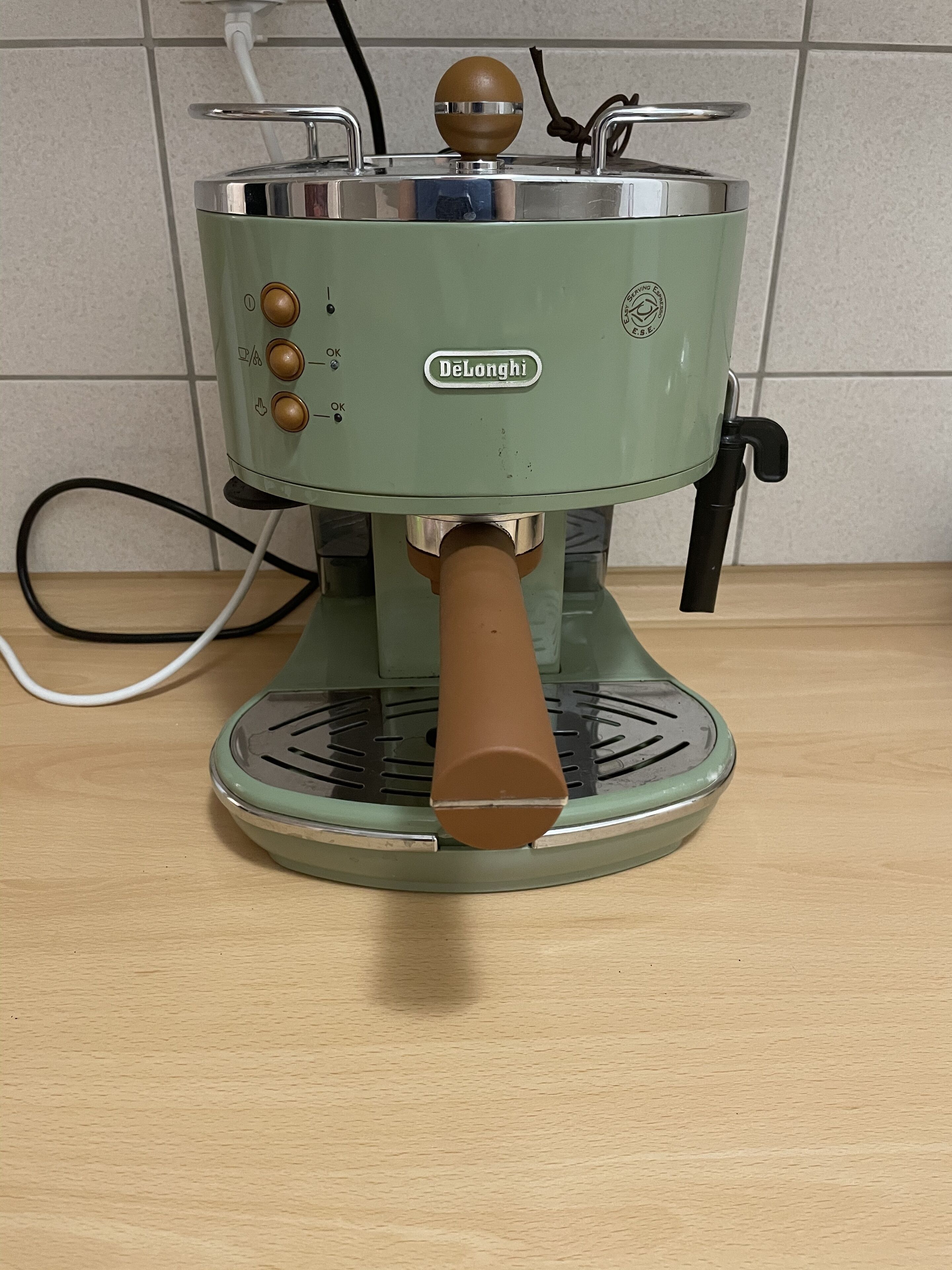 A vintage DeLonghi espresso machine with a brown handle, control knobs, and a metal top.