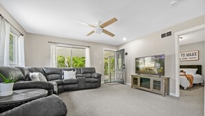 A living room with a sectional sofa, a television, and a ceiling fan. - Higgins Hideout *3 minute drive to the beach* (Roscommon)