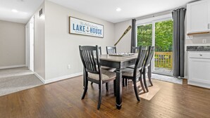 A dining area with a wooden table and chairs, a framed sign on the wall, and a view of the outdoors through a sliding glass door. - Higgins Hideout *3 minute drive to the beach* (Roscommon)
