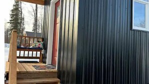 Una escalera de madera que lleva a una puerta principal con marco rojo.