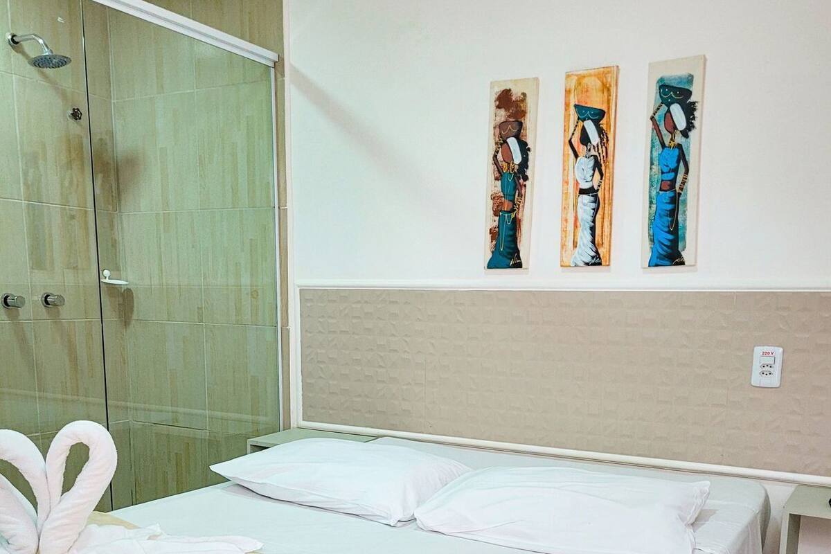 Een hotelkamer met een bed, een douche en drie schilderijen aan de muur.