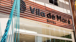 Exterior del hotel Vila de Mare con fachada moderna, amplios ventanales de vidrio y un letrero llamativo.