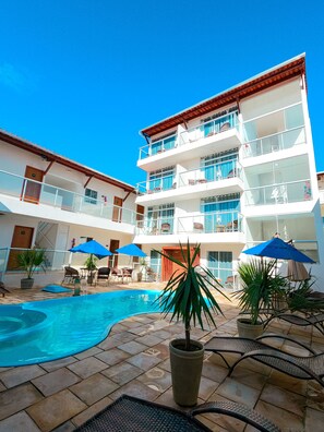 Et hotel med swimmingpool, udendørs siddepladser og flere balkoner.