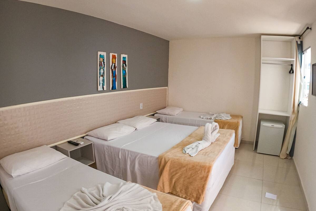 Een hotelkamer met twee bedden, een tafeltje, een spiegel en een kledingkast.