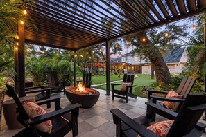 An outdoor patio with a fire pit, seating, and string lights. - Lux Vacay Near AMI & IMG: PCKL Ball, Pool, Put Put (Bradenton)