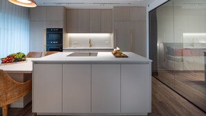 A modern kitchen with a central island, built-in appliances, and a glass-enclosed bathroom. - Tripel-A (Tel Aviv)