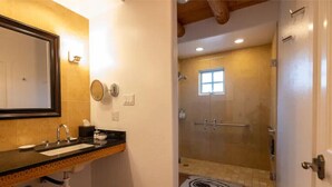 A bathroom with a sink, mirror, and shower area.