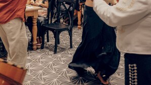 A group of people dancing in a room with a geometric patterned floor, large windows, and indoor plants. - Yum Kaax Boutique Villa (Tulum)