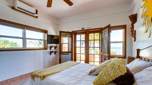 Ein Schlafzimmer mit einem Bett, einem Fernseher, einem Fenster und einer Tür, die nach draußen führt.