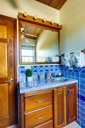 Ein Badezimmer mit Holzausstattung, einer blauen Fliesenrückwand und einem Spiegel mit Beleuchtung darüber.