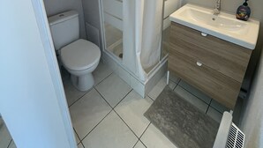 A bathroom with a shower, toilet, sink, and mirror. - Charming apartment in Sète close to all amenities, secure parking. (Sète)