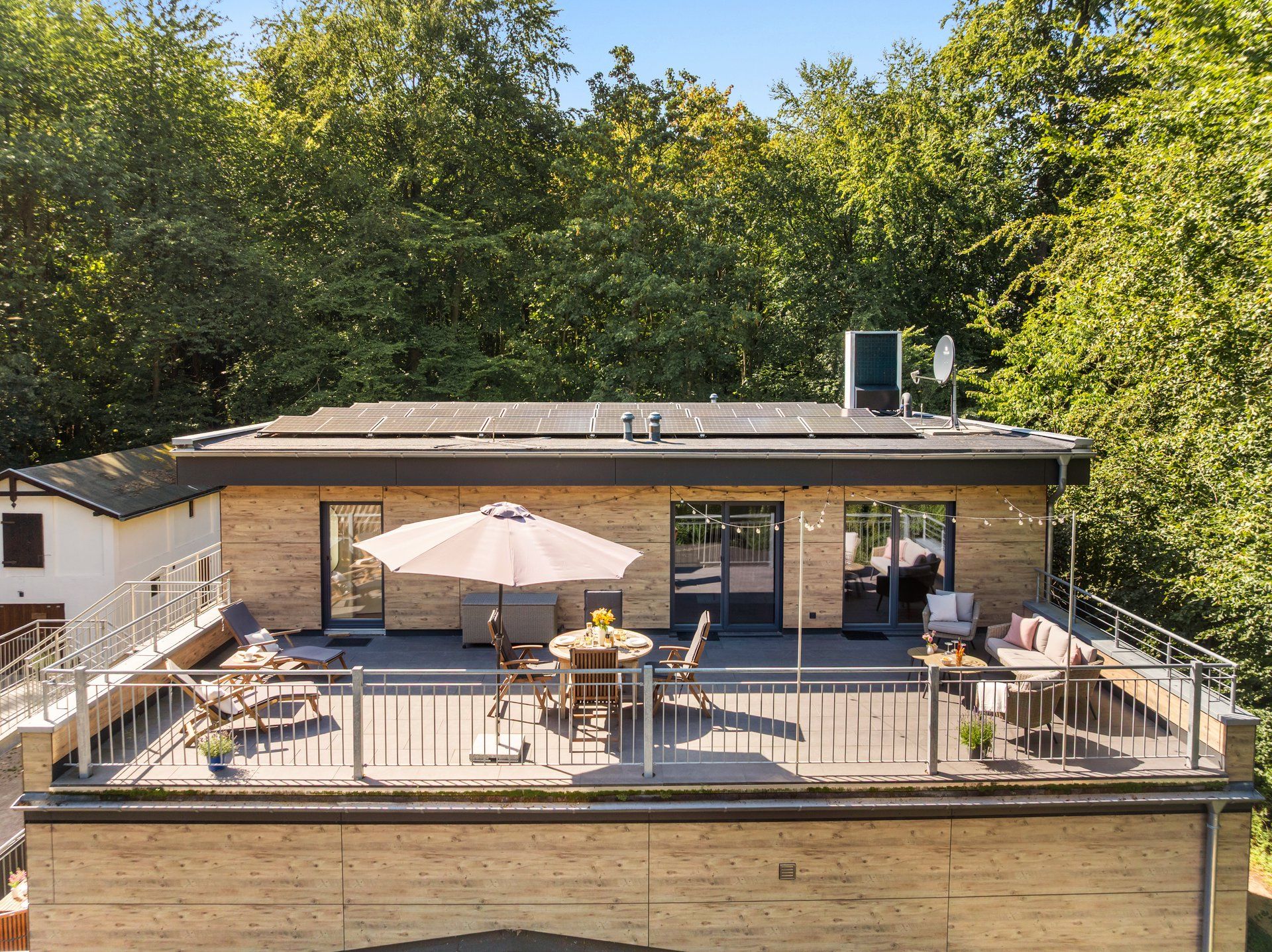 Um edifício moderno com terraço, área de estar ao ar livre e painéis solares.
