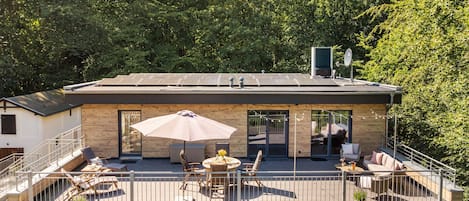 A modern building with a deck, outdoor seating, and solar panels.