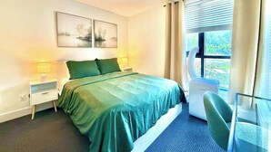 A hotel room with a bed, two bedside tables, a chair, a window with curtains, and a ceiling light. - New Downtown Townhouse, Free Parking Near SkyTrain (Surrey)