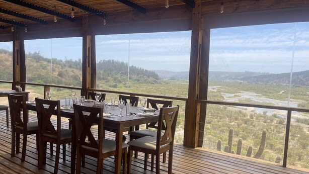 A wooden deck with a table set for dining, overlooking a scenic landscape. - Santo Domingo Lodge (Santo Domingo)
