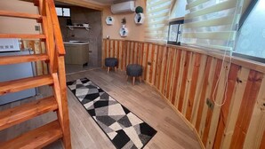 A cozy cabin interior with a wooden staircase, a kitchen area, and a window with blinds. - Santo Domingo Lodge (Santo Domingo)