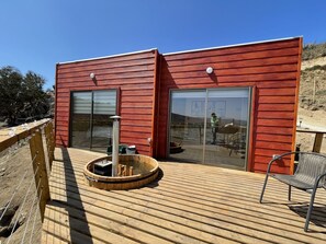 Ein modernes Gebäude mit roter Fassade, großen Glasüren und einer Holzterrasse.