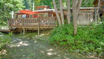 A wooden cabin with a deck and a red umbrella.