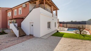 A two-story house with a white exterior, a wooden balcony, and a swimming pool. - Stunning home in Pula (Pula)