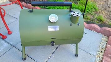 A green outdoor grill with a temperature gauge, a label reading "MAISON HUIS," and a handle on top.
