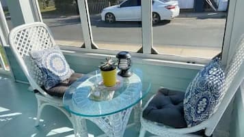A glass-top table with two wicker chairs, each with patterned cushions, and a small decorative item on the table.