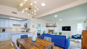 Eine moderne Küche mit weißen Schränken, einem Holztisch und einem blauen Sofa im Wohnbereich.