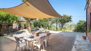 An outdoor patio with a table and chairs, a shade sail, and a view of the surrounding landscape. - Amazing home in Castellabate with WiFi (Castellabate)