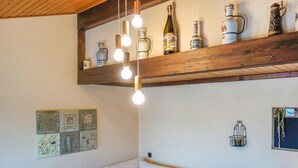 A cozy living room with a wooden ceiling, a sofa with cushions, a wall-mounted shelf with decorative bottles, and a light fixture. - Awesome home in Meschede with WiFi (Meschede)