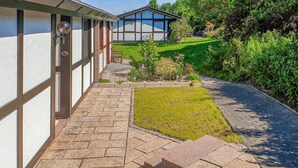 A pathway leading to a building with a brick facade and a small garden area with grass and shrubs. - Awesome home in Meschede with WiFi (Meschede)