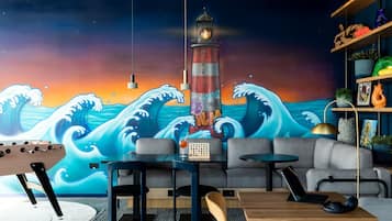 Relax in a stylish space with a vibrant mural of a lighthouse and ocean waves, perfect for unwinding with a good book or music.