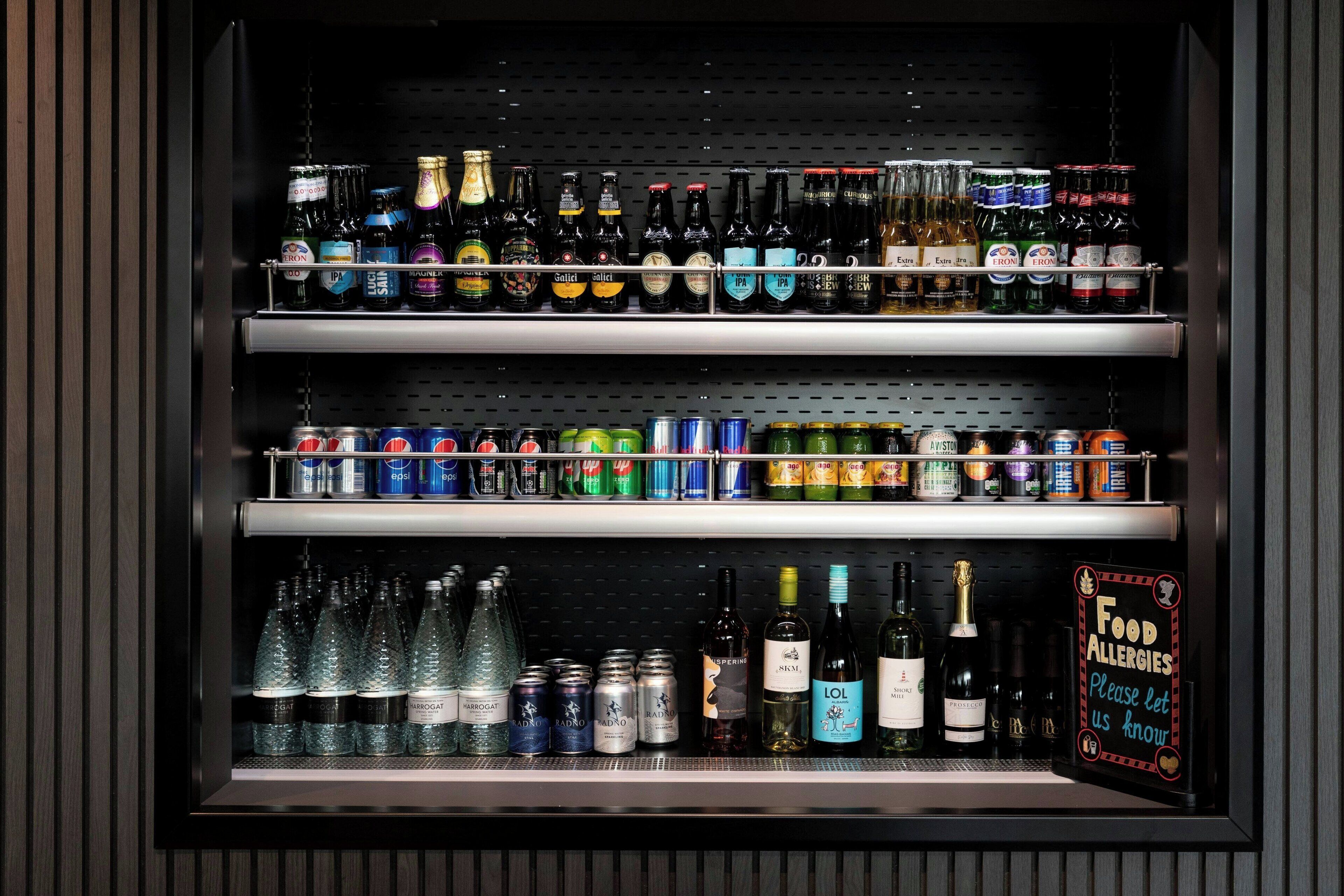 A refrigerated display case with various beverages including beers, wines, and canned drinks.