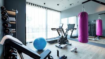 Un gimnasio con equipamiento de ejercicio, un saco de boxeo y un amplio ventanal que proporciona luz natural.
