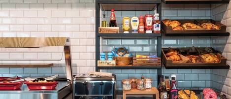 Una cocina con un tostador, estantes con condimentos y una bandeja de pasteles.