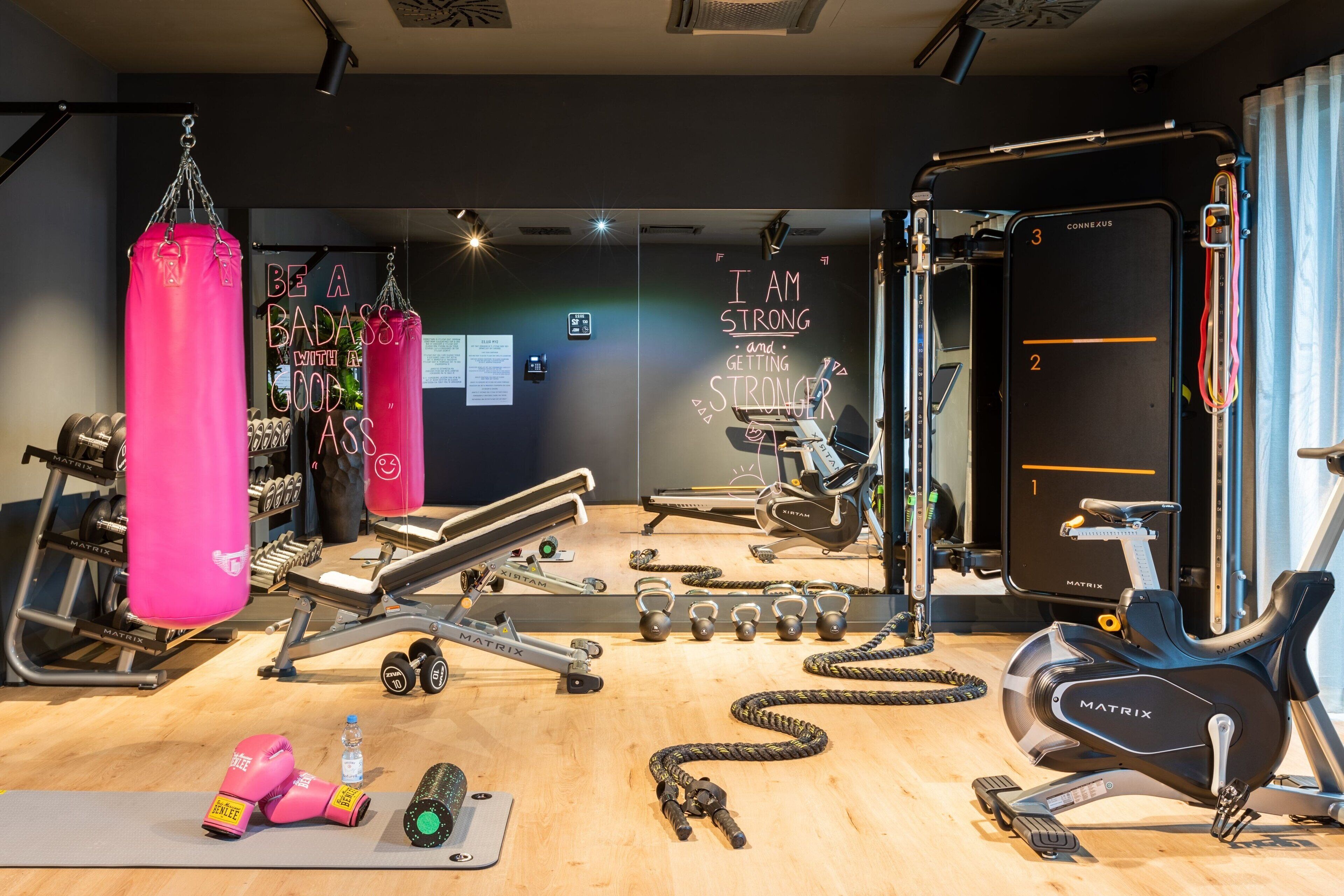 A gym with various exercise equipment, including punching bags, dumbbells, and a stationary bike.