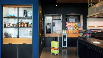 A modern kitchen with a microwave, various food items, and a suitcase.