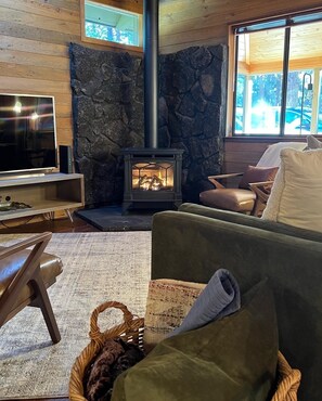 A cozy living room with a stone fireplace, wooden walls, and comfortable seating. - Wooden A-Frame Cabin Nestled in the Tall Pines (Sisters)