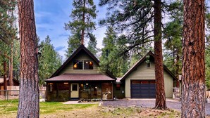 Eine Hütte mit einer großen Veranda, einer Garage und einem überdachten Sitzbereich im Freien.