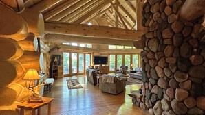 L’intérieur d’une cabane en rondins, avec un mur en pierre, un plancher en bois et une cheminée.
