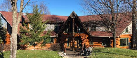 Une cabane en rondins avec des fondations en pierre, une terrasse en bois et un ciel dégagé.